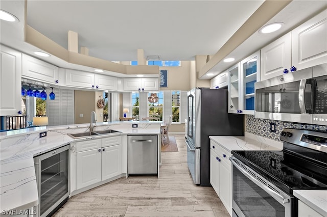 kitchen featuring white cabinets, stainless steel appliances, kitchen peninsula, and wine cooler