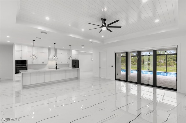 unfurnished living room with wooden ceiling, a raised ceiling, sink, and ceiling fan