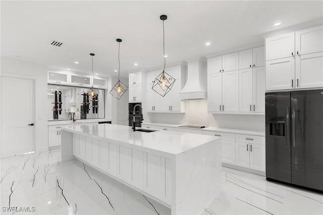 kitchen featuring premium range hood, decorative light fixtures, white cabinetry, black appliances, and light stone countertops