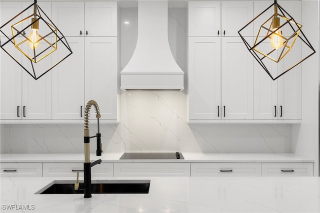 room details with white cabinetry, tasteful backsplash, light stone countertops, premium range hood, and sink