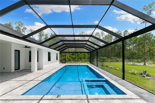 view of pool featuring glass enclosure, a yard, ceiling fan, and a patio