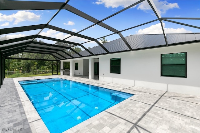 view of pool with glass enclosure and a patio area