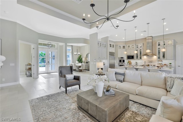 living room featuring a chandelier, baseboards, french doors, a raised ceiling, and crown molding