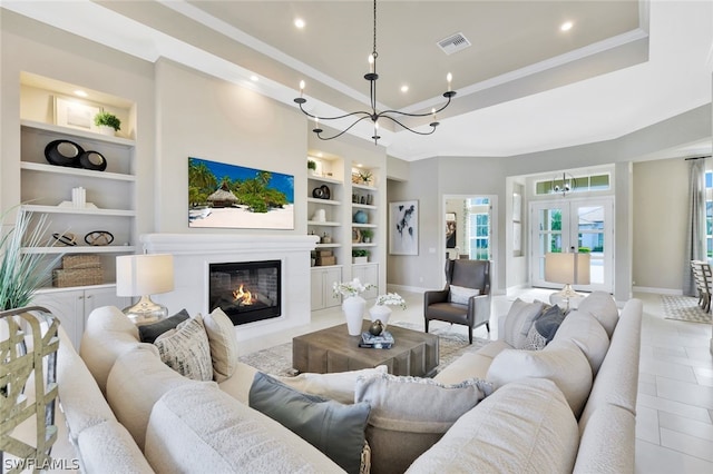 living room with french doors, built in shelves, ornamental molding, light tile patterned floors, and a chandelier