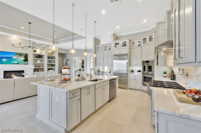 kitchen with light stone counters, stainless steel appliances, a spacious island, sink, and hanging light fixtures