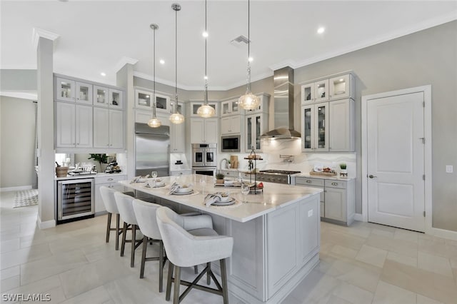 kitchen featuring decorative light fixtures, built in appliances, wall chimney exhaust hood, a large island, and beverage cooler