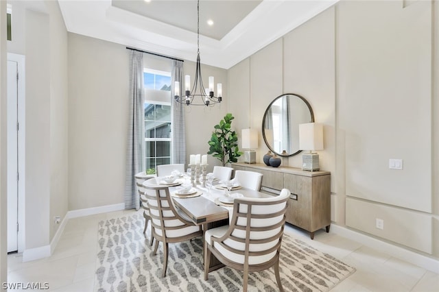 tiled dining area with a raised ceiling and a chandelier