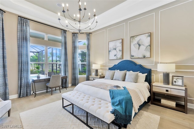 bedroom featuring a chandelier, light wood-type flooring, and a tray ceiling