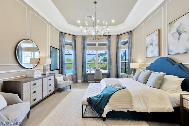 bedroom featuring crown molding, light hardwood / wood-style flooring, a tray ceiling, and a chandelier