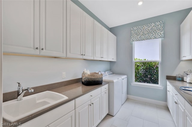 laundry room with sink, light tile patterned floors, cabinets, and independent washer and dryer