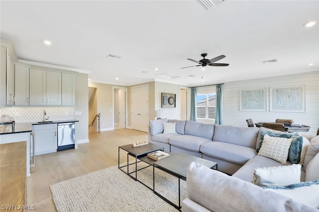 living room with ceiling fan, light hardwood / wood-style flooring, sink, and wooden walls