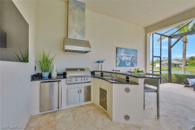 kitchen with kitchen peninsula, a kitchen bar, dark stone counters, sink, and stainless steel refrigerator