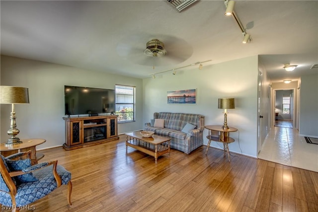 living room with light hardwood / wood-style floors, track lighting, and ceiling fan