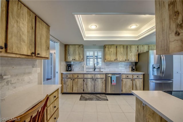 kitchen featuring appliances with stainless steel finishes, backsplash, a raised ceiling, crown molding, and sink