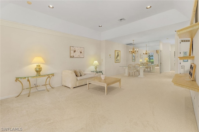 carpeted living room featuring a tray ceiling and an inviting chandelier