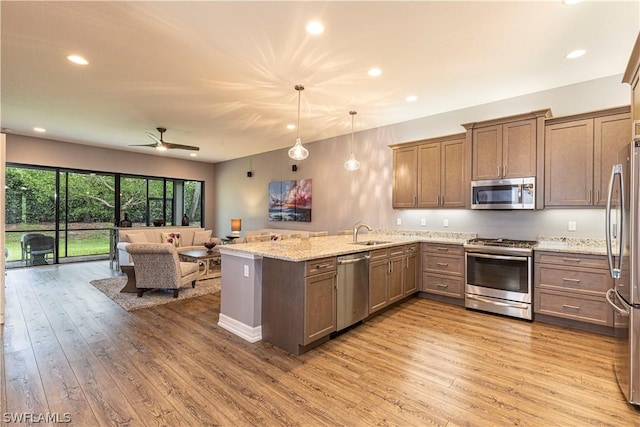 kitchen with kitchen peninsula, light wood-type flooring, decorative light fixtures, and appliances with stainless steel finishes