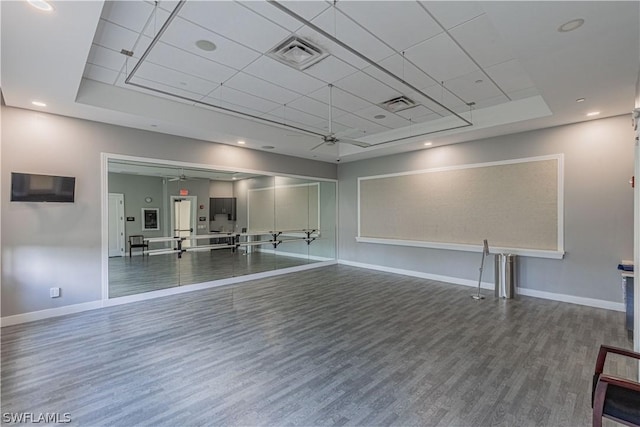 interior space featuring a raised ceiling, ceiling fan, and wood-type flooring