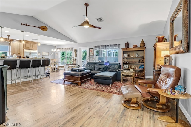 living room with vaulted ceiling, ceiling fan with notable chandelier, and light hardwood / wood-style floors