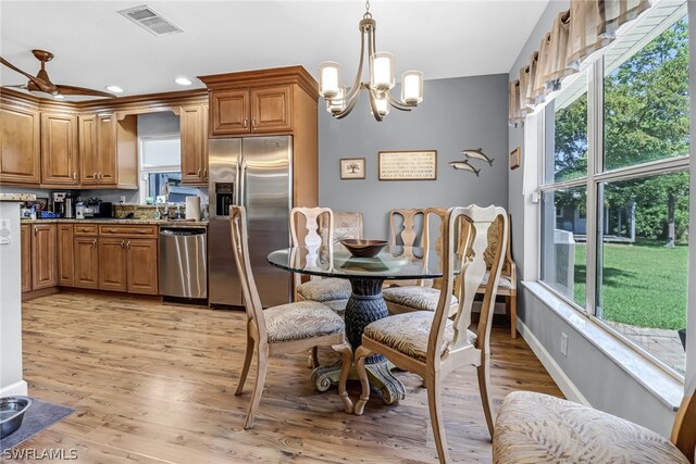 dining room featuring light wood-type flooring, ceiling fan with notable chandelier, and plenty of natural light