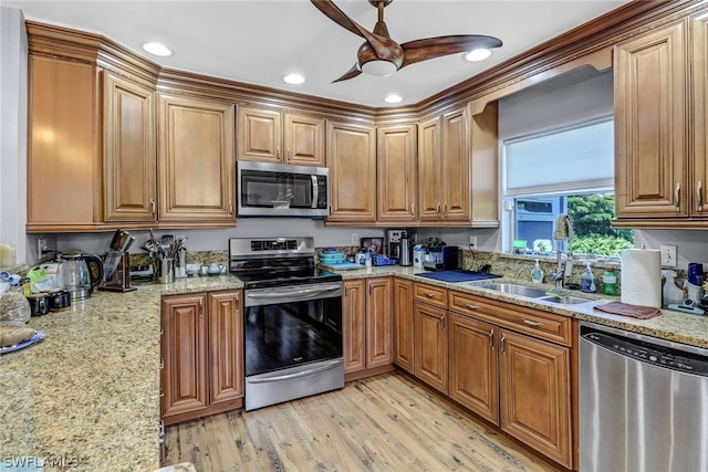 kitchen with light wood-type flooring, ceiling fan, stainless steel appliances, light stone countertops, and sink