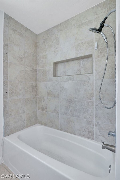 bathroom featuring tile patterned flooring and tiled shower / bath