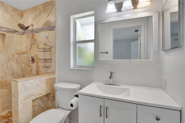 bathroom with a tile shower, vanity, and toilet