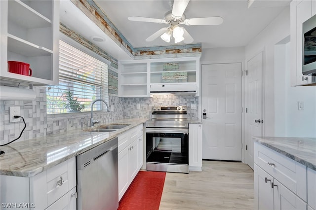 kitchen with light stone countertops, stainless steel appliances, white cabinetry, and sink