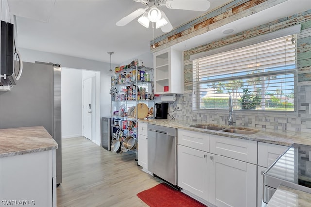 kitchen with white cabinetry, sink, light stone countertops, decorative backsplash, and appliances with stainless steel finishes