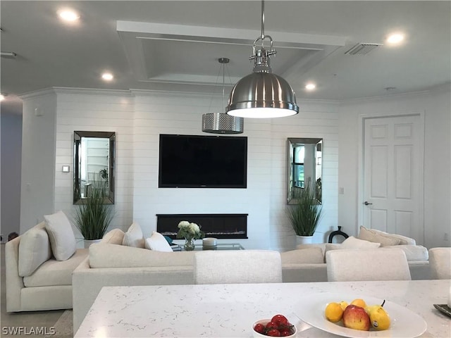 living room featuring a tray ceiling, a fireplace, and ornamental molding