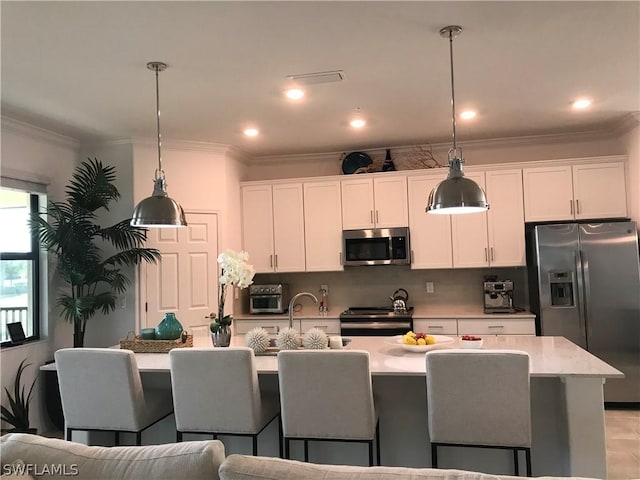 kitchen featuring white cabinetry, an island with sink, pendant lighting, and appliances with stainless steel finishes