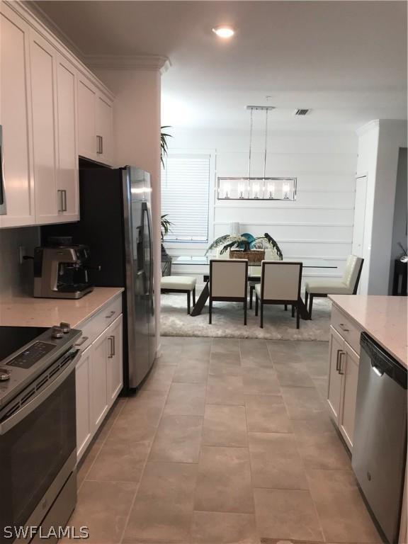 kitchen featuring white cabinetry, stainless steel appliances, and decorative light fixtures