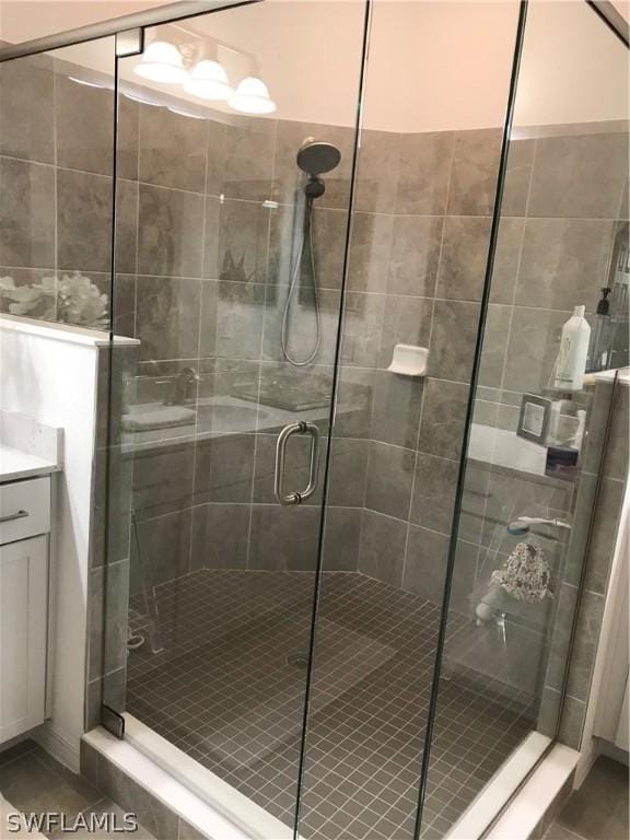 bathroom with tile patterned flooring, vanity, and a shower with door