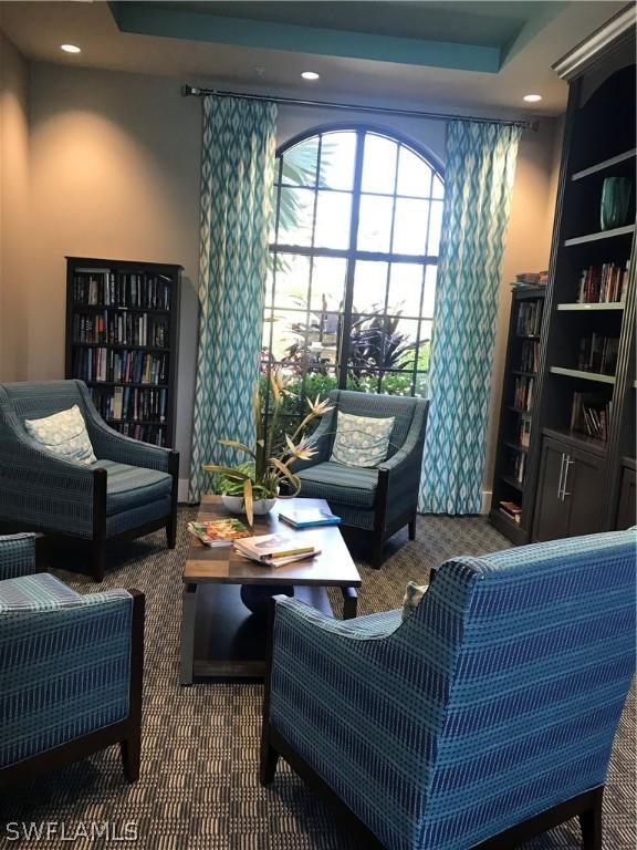 living area with built in features, a tray ceiling, and dark carpet