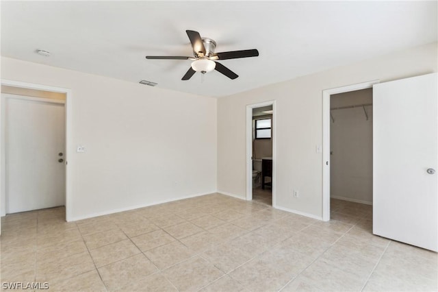 unfurnished bedroom with a walk in closet, a closet, light tile patterned flooring, ceiling fan, and ensuite bathroom