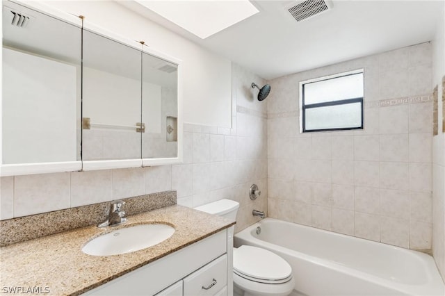 full bathroom with tiled shower / bath, vanity, backsplash, toilet, and tile walls