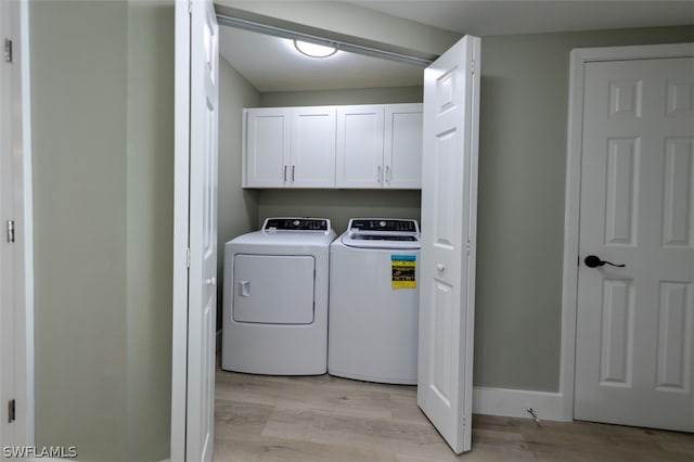 laundry area with cabinets, light wood-type flooring, and washing machine and clothes dryer