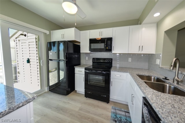 kitchen with tasteful backsplash, light stone counters, sink, black appliances, and white cabinets