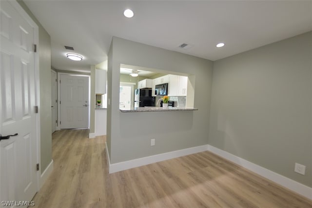 unfurnished room featuring light wood-type flooring, visible vents, and baseboards