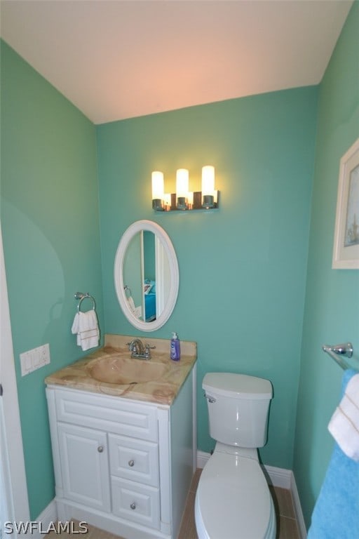 bathroom featuring toilet, baseboards, and vanity