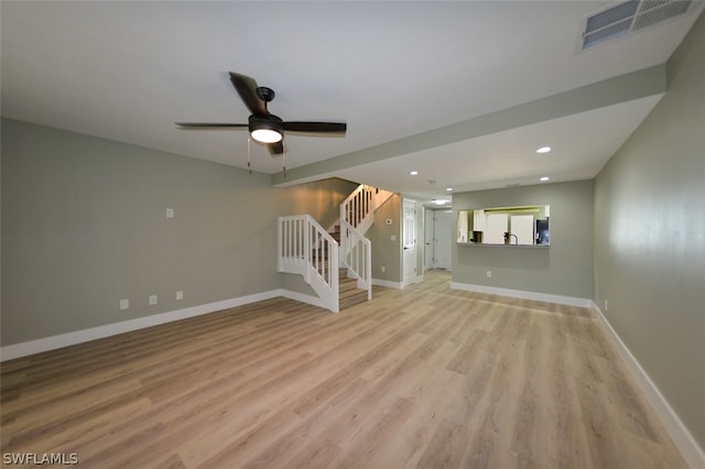 unfurnished living room featuring light wood-type flooring, visible vents, baseboards, and stairs