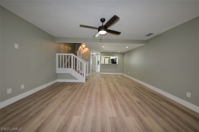 unfurnished living room featuring stairs, light wood-style flooring, and baseboards