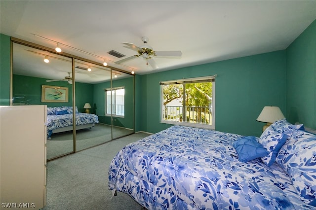 carpeted bedroom with ceiling fan, rail lighting, and a closet