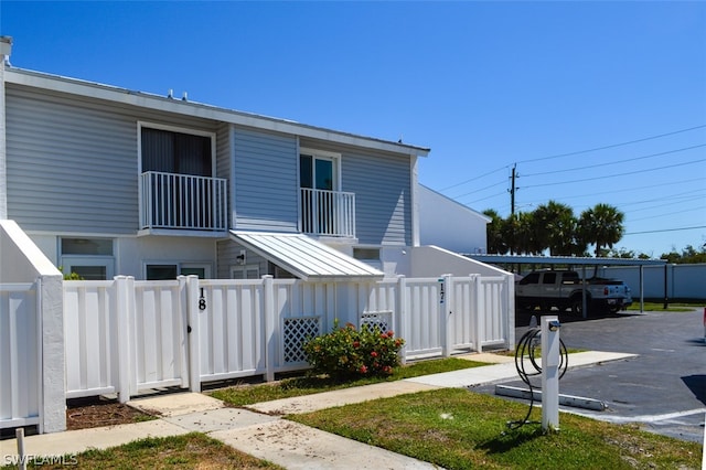 exterior space with a balcony, a fenced front yard, and a gate