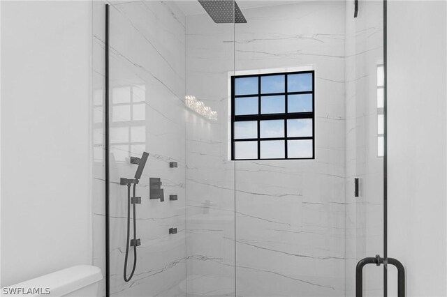 bathroom featuring a shower with shower door and toilet