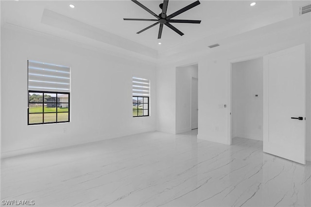 spare room with a raised ceiling and ceiling fan