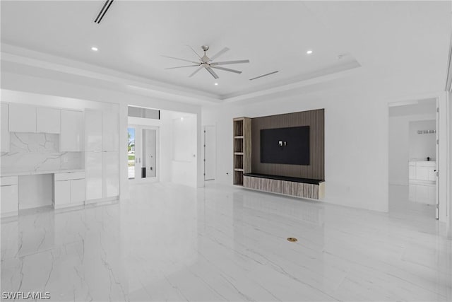 unfurnished living room with ceiling fan, a fireplace, and a tray ceiling