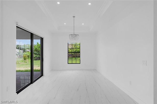 spare room with a raised ceiling and an inviting chandelier