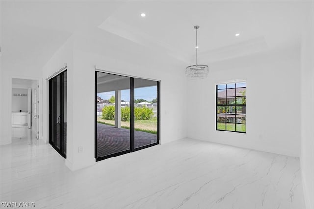 spare room with a raised ceiling and an inviting chandelier