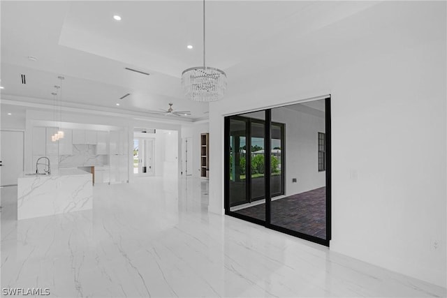 unfurnished room featuring ceiling fan with notable chandelier, a raised ceiling, and plenty of natural light