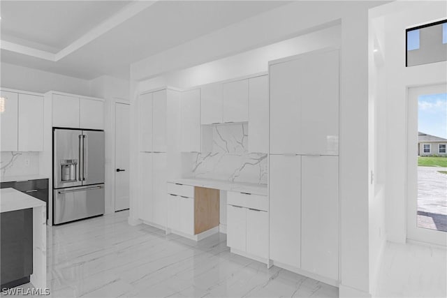 kitchen featuring high end fridge, white cabinetry, and tasteful backsplash